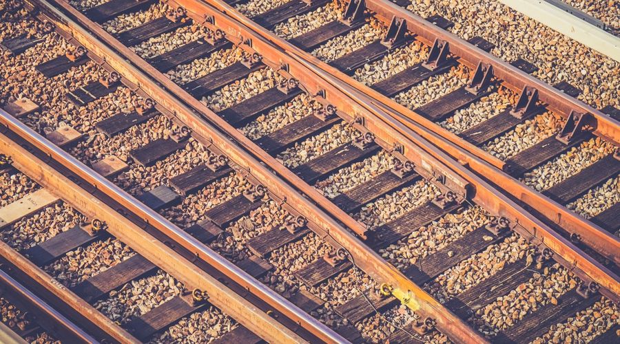 Rusty-hued closeup photograph of tracks running through a train yard